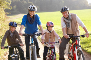 Young family pose with bikes in park