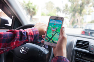 Los Angeles,California, USA - July 30, 2016: Man holding a smartphone and playing Pokemon Go in the car. Pokemon Go is a popular location based augmented reality mobile game.